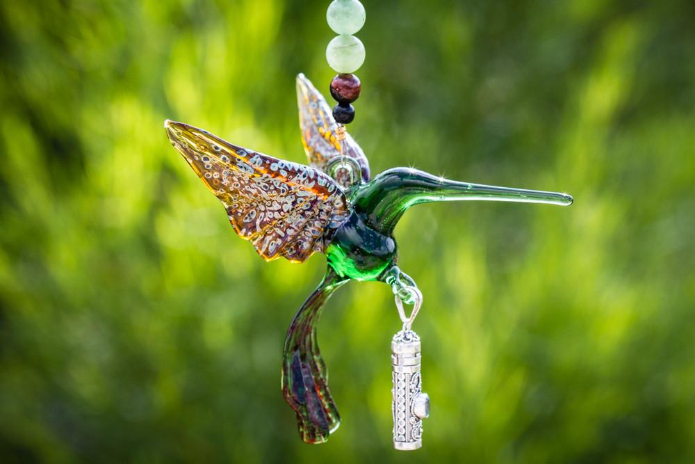 Green glass hummingbird ornament suspended with a strand of pale green beads and darker accents, featuring a silver keepsake urn pendant.