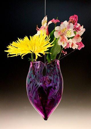 Dual-necked hanging glass vase in deep purple with blue accents, holding yellow chrysanthemum and pink white blossoms