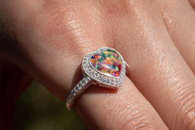 Bedazzled Heart Cremation Ring with rainbow selection of crushed opal. The ring is being worn by a model. Sterling Silver Ring for Ash, Sterling Silver Memorial Jewelry, Remembrance Jewelry, Silver Ring