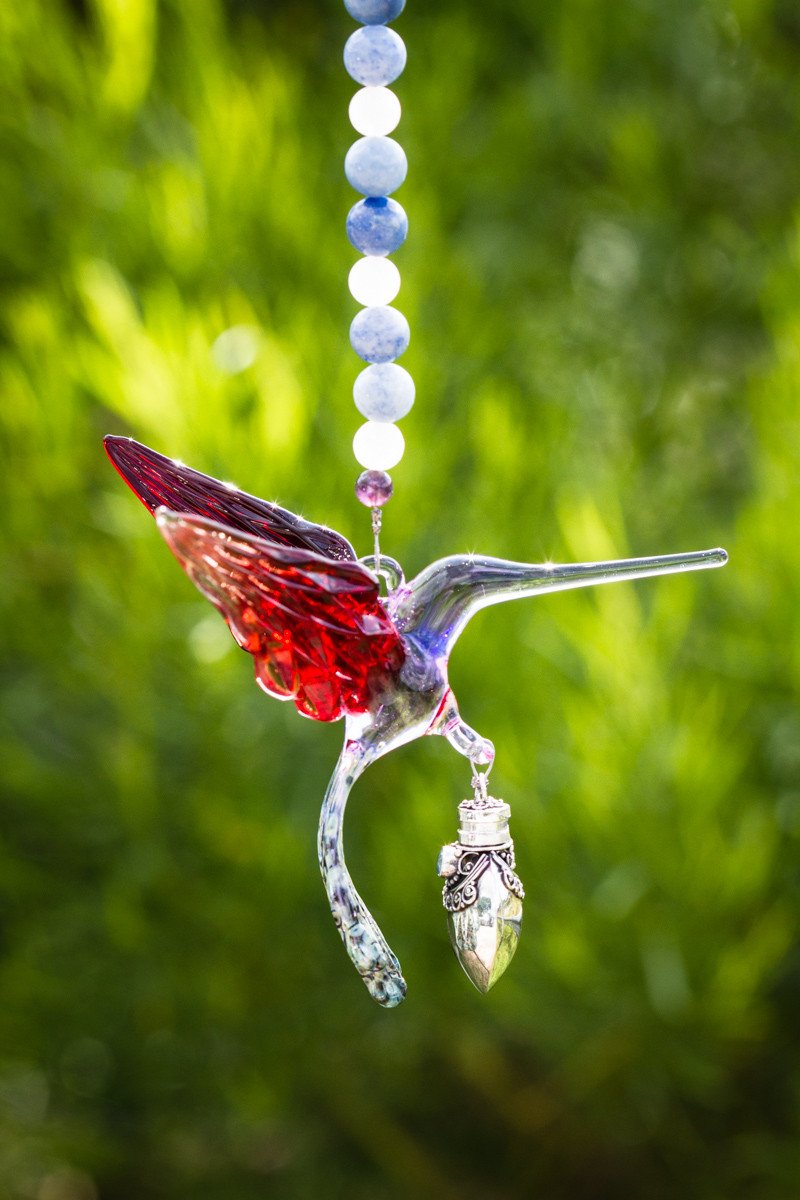 Handmade glass hummingbird pendant with red wings, blue and white bead strand, and a silver keepsake urn charm.