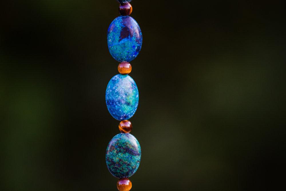 Vertical strand of turquoise blue beads with small orange spacers against a dark background