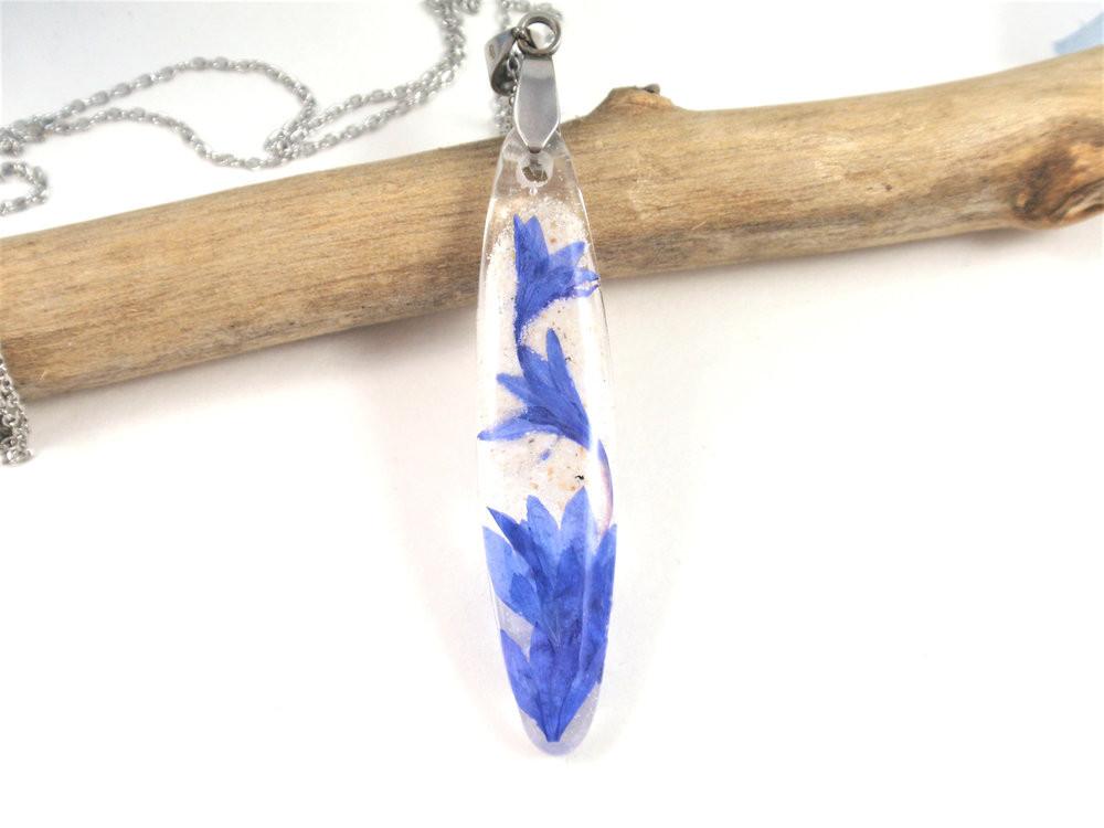 Close-up of crystal resin cornflower pendant with blue petals and a silver chain.