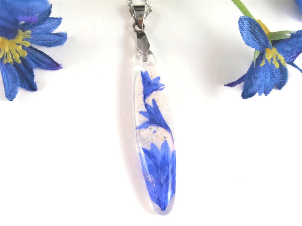 Front view of pendant with blue cornflower suspended in clear resin and a metal chain.