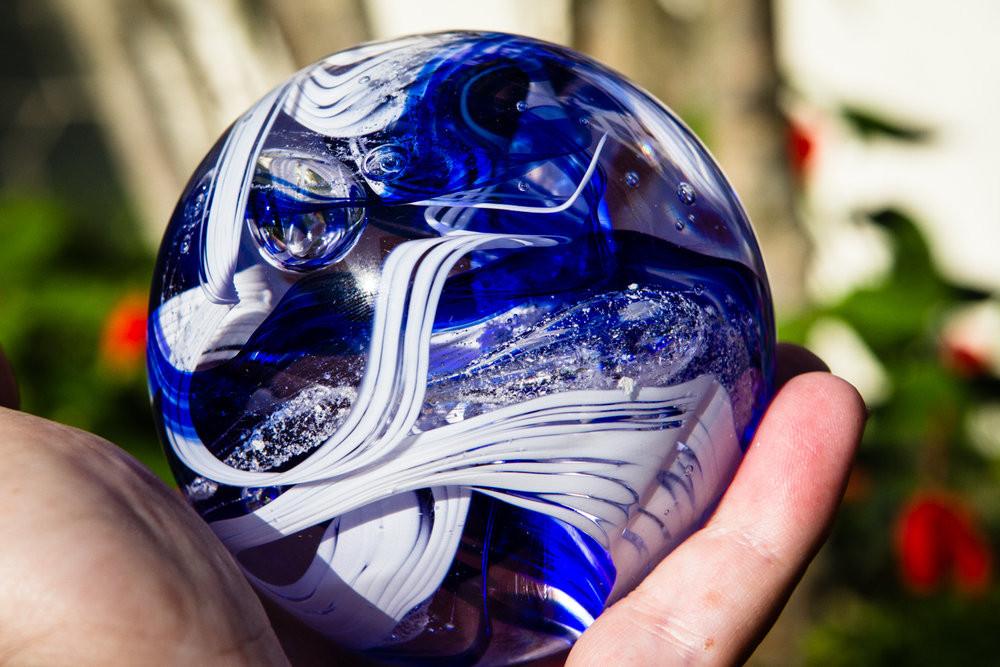 Dark blue and white opaque banner orb with swirled glass held in hand