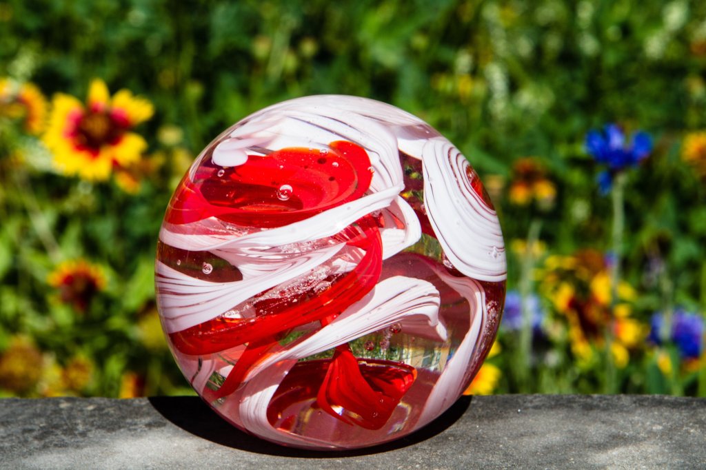 Red and white swirled opaque banner orb resting on a stone outdoors