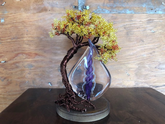 Copper wire Tree of Life with a yellow blossom canopy and purple memorial flame in a glass teardrop vase.