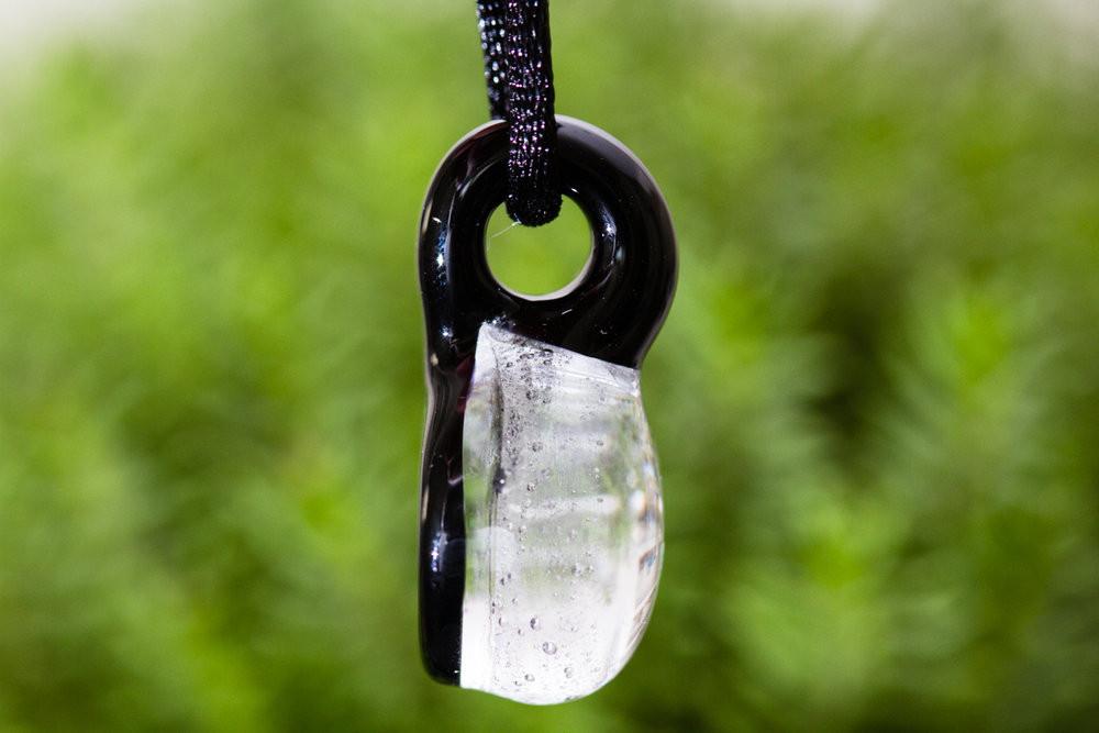Pawprint hologram pendant infused with cremation ashes, shown with a purple hue and suspended from a cord.