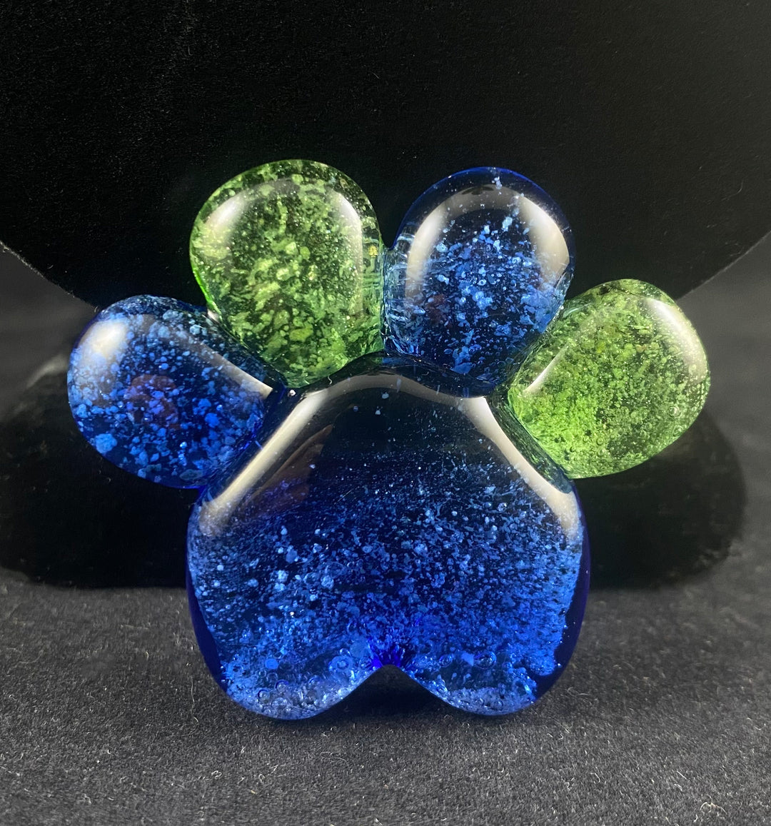 Glass paw print pendant with a blue base and multicolor toe pads in green and blue
