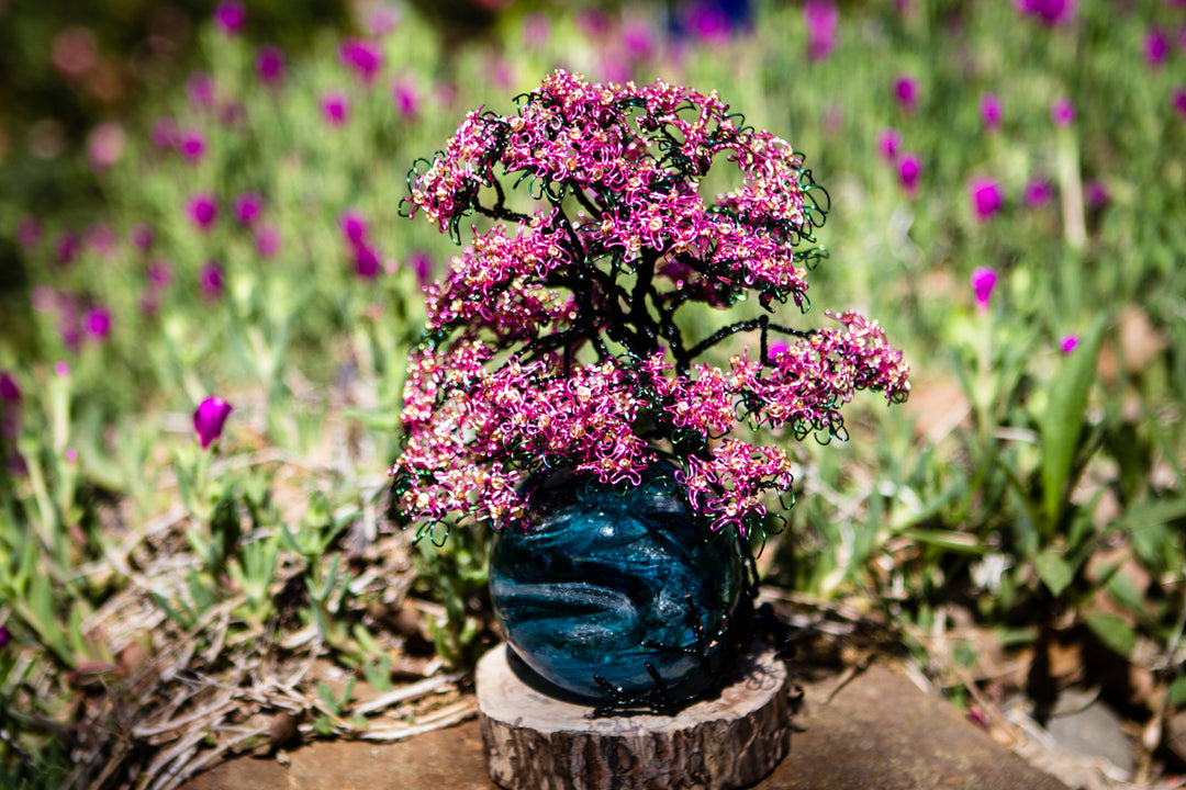 Handcrafted pink dogwood tree wire sculpture mounted on a wooden base with delicate blossoms.