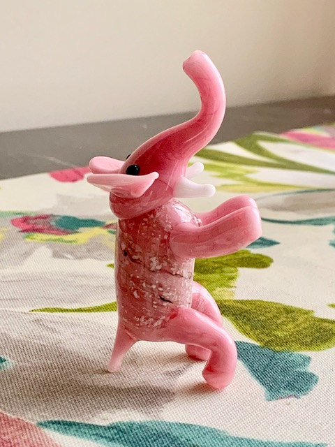 Pink glass elephant figurine infused with cremation ash standing on a table