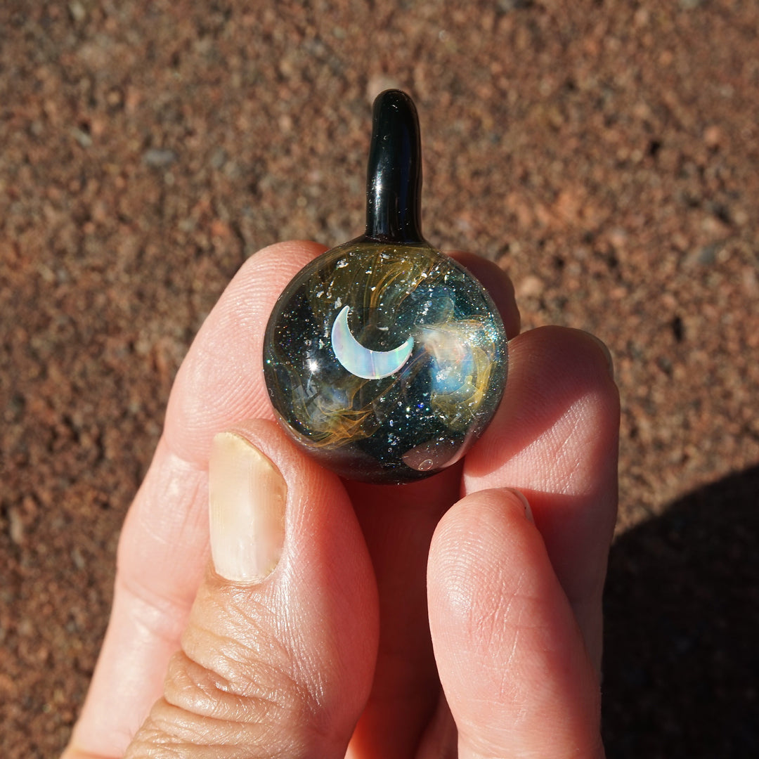 Close-up of galaxy glass pendant featuring a pale star within iridescent swirls and cremains.