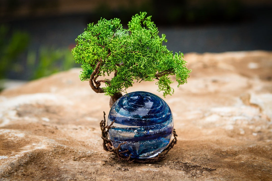 Ponderosa Tree of Life with Sparkle Orb resting on a rocky surface with a green wire tree and blue orb