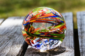 rainbow confetti orb with cremation ash sitting on bench