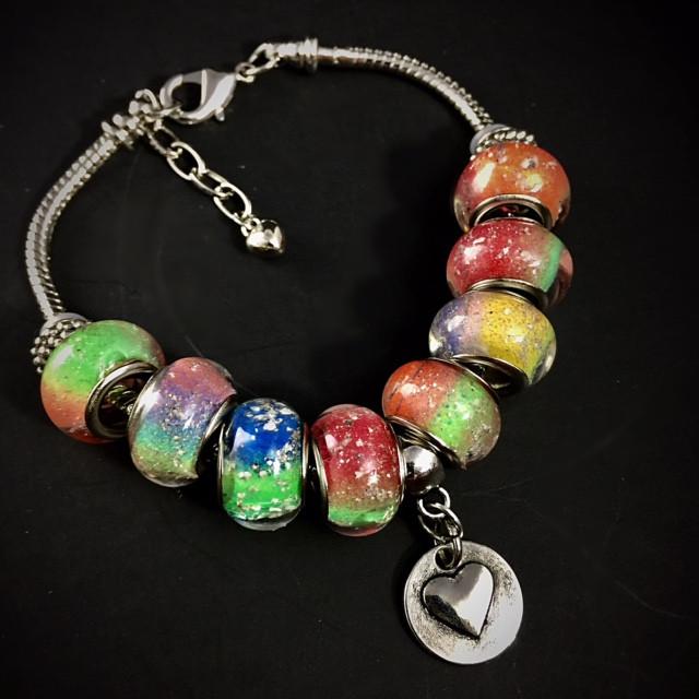 Beaded Rainbow's Bridge bracelet showing eight colorful infused beads and a silver heart charm