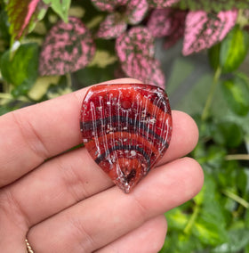 guitar pick with cremation ash red in hand
