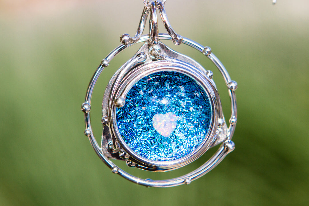 Caged Heart in Stars pendant containing a blue glitter cabochon and a heart shaped opal inside