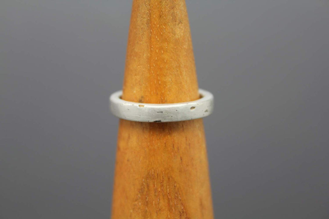 Silver cremation ash ring displayed on a wooden stand with a simple band design
