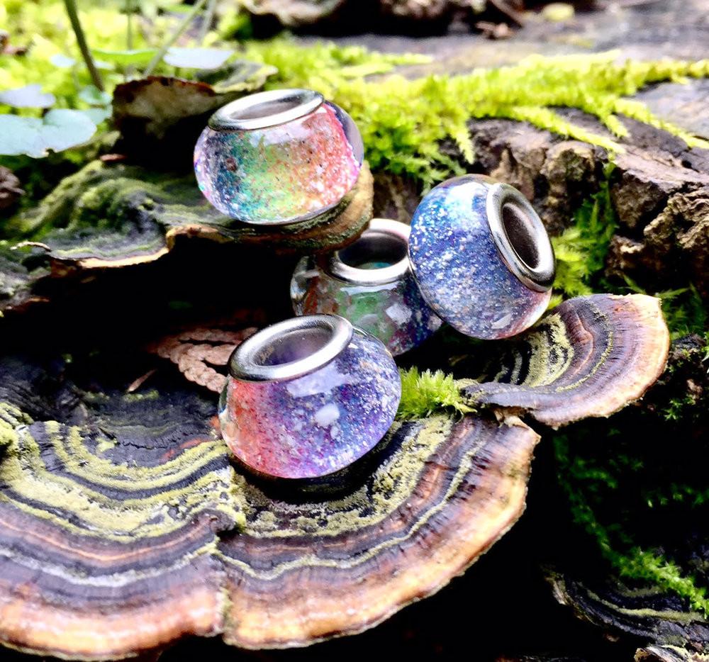Rainbow glass beads infused with cremation ashes arranged on a mossy log