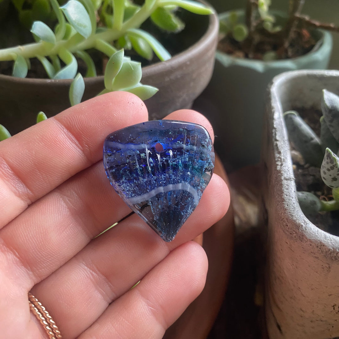 guitar pick with cremation ocean blue green in hand