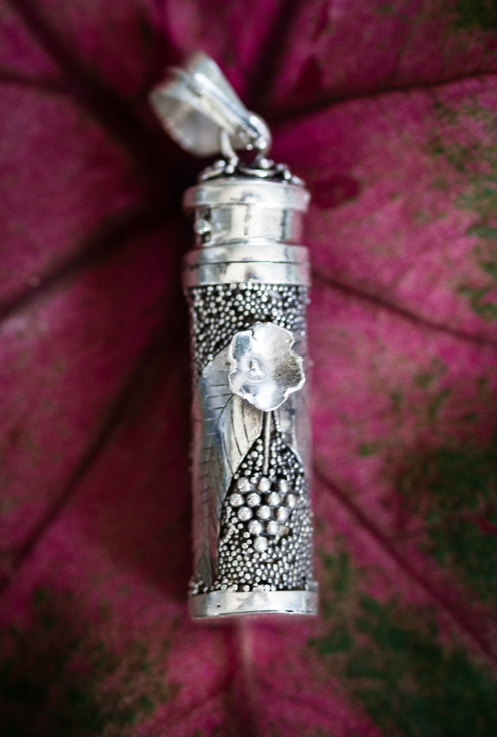 Sterling silver keepsake pendant with a three dimensional flower and beaded surface, twist off top.