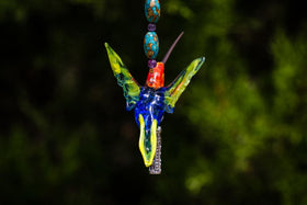 Vivid handmade glass hummingbird pendant with a sterling silver cylinder keepsake capsule for cremains on a beaded chain.