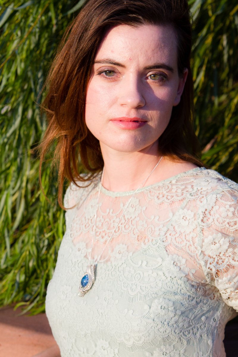 Portrait of a woman wearing the Madison wire wrapped pendant with a blue cabochon containing cremation ashes on a silver chain.