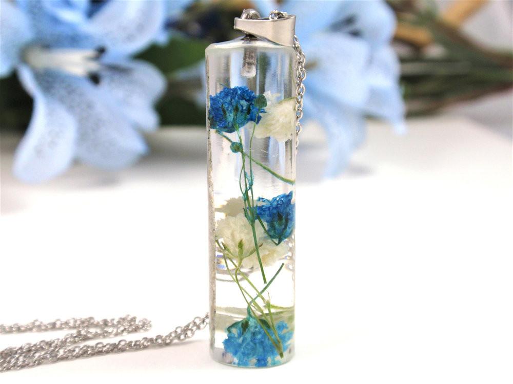 Glass pendant necklace containing blue and white baby's breath preserved in clear resin with infused ashes.