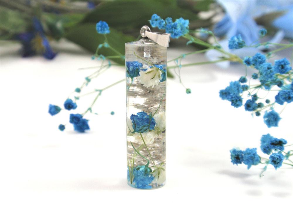 Vertical crystal resin pendant filled with blue flowers and white blooms on a stainless steel chain