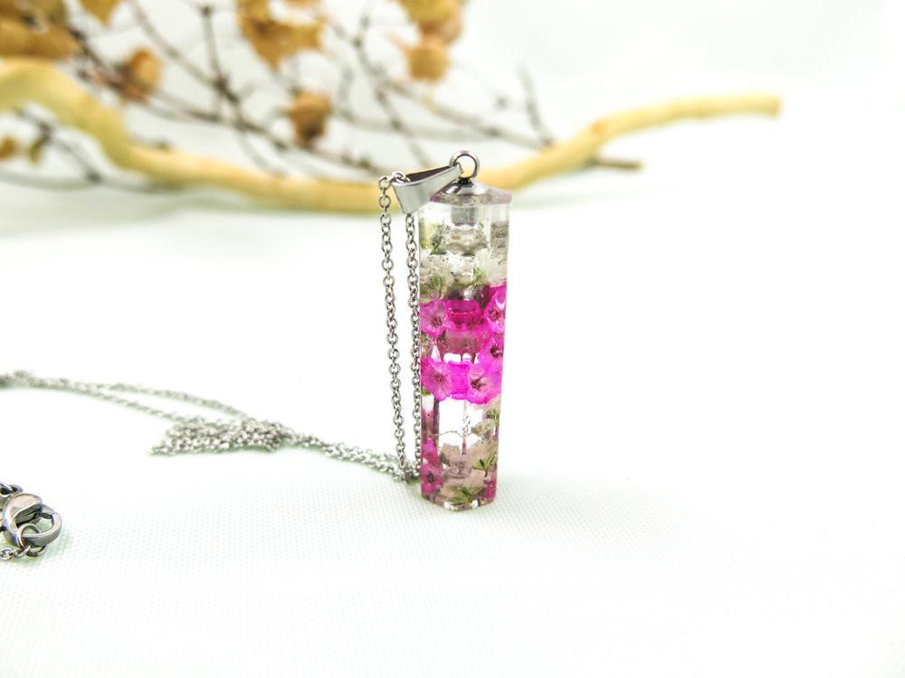 Crystal resin pendant containing white baby's breath and pink sinensis flowers on a stainless steel chain.