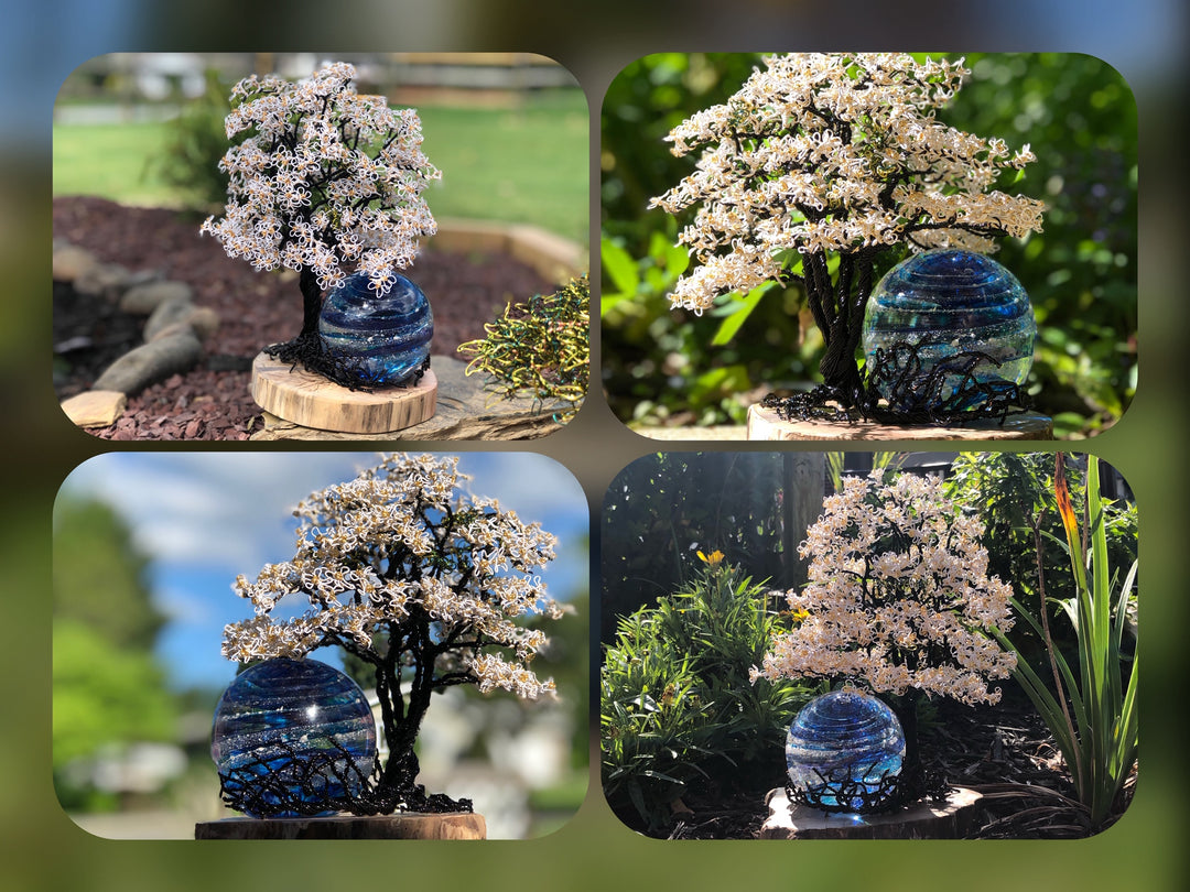 White Dogwood Tree of Life with Sparkle Swirl Orb on a wooden stand in a sunny garden setting.